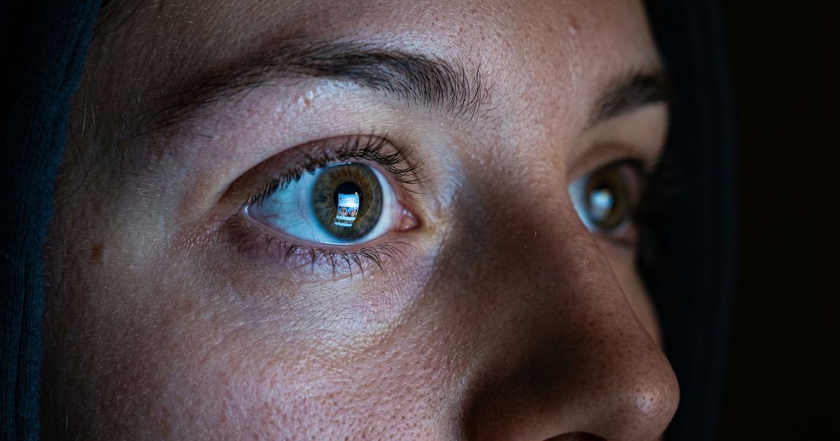Close-up of an eye reflecting a smartphone screen — the neuroscience of brain rot from scrolling